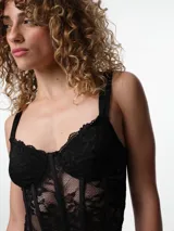 Corset de encaje negro con estructura de ballenas, copa preformada con aro y breteles elásticos ajustables.