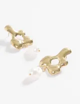Aros colgantes con forma de flor irregular dorada, con centro calado y dije de perla colgante.