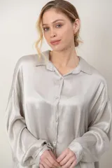 Camisa de satén tramada color blanco, con calce holgado y cómodo, cuello camisero, mangas largas y cierre frontal con botones.