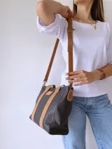 Cartera negra de cuero con forro de tela, doble asa corta y correa larga desmontable.