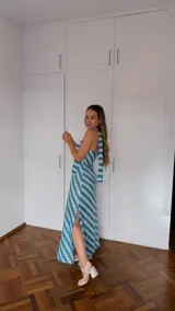 Vestido largo sin mangas, con escote palabra de honor y pañuelo incorporado al cuello. Presenta un estampado geométrico en tonos celeste, verde y blanco, con aberturas laterales en la falda.