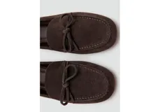 Mocasines de gamuza color marrón oscuro, con detalle de lazo en el empeine y suela plana.