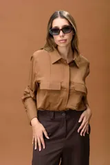 Camisa color habano de corte clásico, con cuello camisero, bolsillos frontales con solapa y puños anchos con detalle de botón metálico.