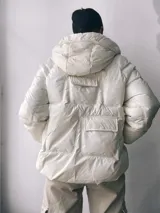 Campera puffer blanca con capucha, cierre frontal con cremallera y bolsillos con solapa en el pecho.