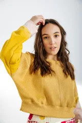 Buzo amarillo mostaza de tejido de punto acanalado, con mangas largas acampanadas y puños en color rosa claro.