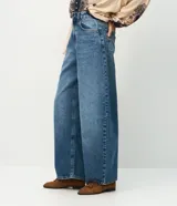Pantalón barrel de jeans de tiro medio, con piernas amplias y afuniladas en el ruedo. Posee bolsillos funcionales, trabillas y cierre delantero con botón y cremallera.