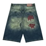 Bermuda de jean estilo baggy con lavado verde desgastado. Presenta grandes bolsillos traseros con bordados en hilo rojo que simulan caracteres chinos.