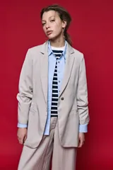 Blazer beige de corte recto, con solapa clásica, bolsillos frontales con solapa y cierre de un botón.