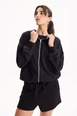 Campera deportiva negra de corte bomber sin friza, con cierre frontal completo, capucha y elásticos ajustables en la cintura.