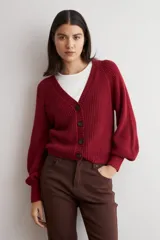 Cardigan de punto acanalado color bordó, con escote en V, cierre frontal de botones y mangas largas abullonadas con puños ajustados.