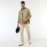Pantalón de corte slim en color beige, confeccionado en tejido de algodón con cierre de botón y cremallera, y bolsillos laterales.