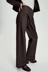 Pantalón de tiro medio en denim oscuro con costuras a contraste. Presenta corte recto, bolsillos delanteros, trabillas en la cintura y cierre frontal con cremallera y ganchos metálicos.