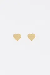 Pendientes tipo broquel con diseño de corazón en acabado metálico plateado y logo grabado en el centro.