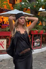 Top lencero de satén negro con escote en V y detalles de encaje en el escote y el ruedo. Presenta breteles finos y un diseño delicado con sutil brillo.