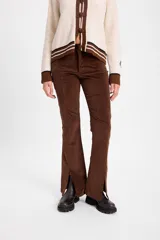 Pantalon de pana color marrón, de corte ajustado con costuras verticales frontales y tajos en el ruedo.