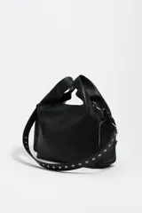 Bolso bandolera de piel vacuna color negro, con estructura blanda y forma hobo o de media luna. Presenta dos bolsillos frontales con cierre metálico plateado y un asa de hombro ancha y ajustable con hebillas y ojales metálicos. El logo de Bimba y Lola está estampado en la parte frontal inferior.