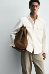 Sobrecamisa de corte regular confeccionada en denim de algodón, con cuello solapa, manga larga con puños abotonados y cierre frontal de botones. Presenta dos bolsillos frontales de plastrón con solapa y bajo con aberturas laterales.