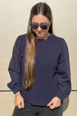 Remera de algodón color azul marino, con cuello redondo fruncido y mangas largas abullonadas con puños elásticos.