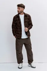 Campera tipo sobrecamisa de franela a cuadros en tonos marrones y verdes, con cuello clásico, cierre frontal de botones y bolsillos con solapa en el pecho.