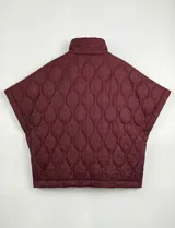 Poncho acolchado color vino tinto, con cuello alto y cierre frontal parcial. Presenta un patrón de costuras capitoné en forma de hoja o diamante y bolsillos delanteros.