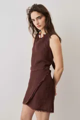 Blusa cropped color chocolate, de silueta suelta y cuello redondo, con terminación de bordes deshilachados.