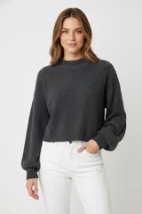 Sweater de tejido de punto grueso, color gris oscuro, con cuello redondo y mangas largas abullonadas.