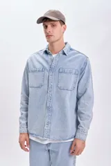 Sobrecamisa de jean celeste con cuello clásico, cierre frontal con botones metálicos, dos bolsillos de parche en el pecho y mangas largas con puños abotonados.