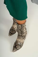 Botín de caña media color beige con estampado de piel de serpiente, punta fina y cierre lateral.