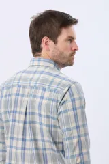 Camisa sport de manga larga con estampado a cuadros en tonos celeste, beige y blanco, cuello abotonado y bolsillo frontal en el pecho.