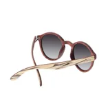 Lentes de sol Indie Hill Stepped con montura redonda de madera color marrón y beige a rayas, y lentes grises degradadas.