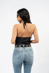 Top halter de tela metalizada negra con escote drapeado y espalda descubierta.