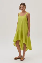 Vestido de lino color lima, corto al frente y más largo en la espalda, con volado en el bajo que aporta movimiento y frescura.