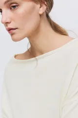 Top de punto fino transparente en color blanco, con mangas largas caídas, amplio escote bote y ribete acanalado ancho en la cintura y los puños.