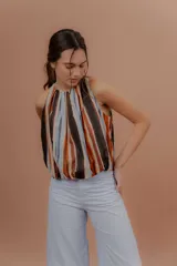 Musculosa de algodón con cuello redondo, sin mangas y diseño abullonado en la parte inferior. Presenta un estampado de rayas verticales en tonos marrones, naranjas, celestes y negros.