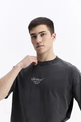 Remera de manga corta color beige, con escote redondo y estampado frontal con la palabra "Surreal" en tipografía cursiva.