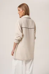 Camisa color beige con bordado de ramas en el frente, de corte holgado y manga larga.