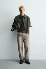 Pantalón de corte relajado confeccionado en tejido de algodón con efecto lavado. Presenta diseño de cinco bolsillos, cierre frontal con cremallera y botón, y detalles de estampados a contraste en la parte delantera y trasera.
