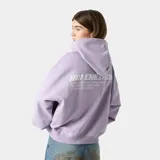 Hoodie oversize color lila con capucha y estampado en la espalda con el logo de Eme Studios y texto que dice "Always grateful for my roots, crafted with care 5135, Veteran Collection".