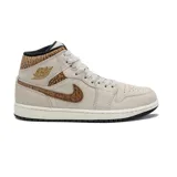 Championes de media caña Air Jordan 1 Mid color beige con detalles en marrón y negro. Presentan el logo de Jordan en el lateral y suela blanca con base negra.