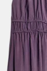 Vestido midi de color morado con cuello halter, tirantes finos ajustables y espalda descubierta. Cuenta con detalles fruncidos en el delantero y la cintura.