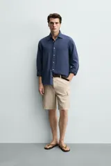 Bermuda cargo regular fit color beige, confeccionada en mezcla de algodón y lino con efecto lavado. Cuenta con bolsillos laterales tipo cargo con solapa en las perneras, bolsillos frontales, cierre frontal con cremallera y botón, y presillas para cinturón.