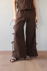 Pantalón negro de tejido ligero, corte holgado, cintura elastizada y aberturas laterales con lazos.