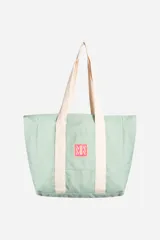 Bolso tipo tote color verde menta, confeccionado en tela canvas. Cuenta con asas largas en color crema, bolsillo exterior frontal con parche de logo y bolsillo interior con cierre.