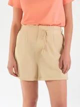 Short de lino color beige, de talle alto con pinzas en el frente, bolsillos laterales y cordón ajustable en la cintura.