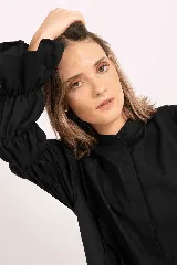 Camisa de lino color negro, con cuello mao, cierre frontal oculto y mangas largas fruncidas con puños amplios.