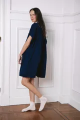 Vestido camisero de corte holgado, color azul marino, con cuello camisero en tono gris claro, cierre frontal completo con botones y mangas cortas. Presenta un diseño funcional ideal para maternidad y lactancia.
