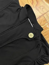 Campera de bengalina con cierre frontal, cuello alto con botón y mangas largas abullonadas con puños abotonados.