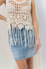 Top tejido artesanal color crudo, confeccionado en punto calado con diseño protagonista. De silueta recta y calce relajado, presenta escote amplio y terminación inferior con flecos.