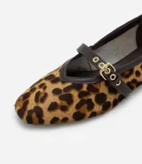 Zapatilla estilo Mary Jane de cuero con estampado animal print de leopardo. Presenta una tira superior ajustable con hebilla metálica dorada y detalles de ribete en color marrón oscuro.