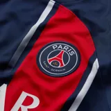 Camiseta de fútbol Nike del Paris Saint-Germain, modelo local temporada 2023/24. Diseño en color azul marino con una franja vertical roja y blanca descentrada hacia la izquierda, patrocinador principal en el pecho y logo de la marca en rojo.